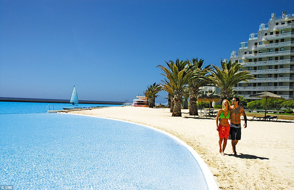 By the sea: A couple stroll along the shores of the artificial lake, which is also the world's deepest swimming pool at 115ft